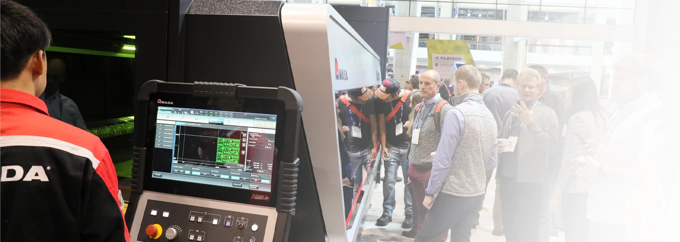 AMADA event calendar background showing trade show attendees