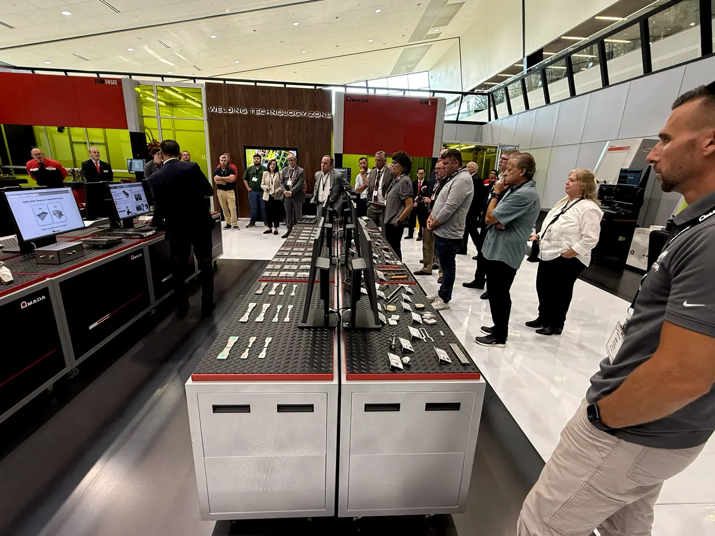 Visitors reviewing welded sample parts on the display table